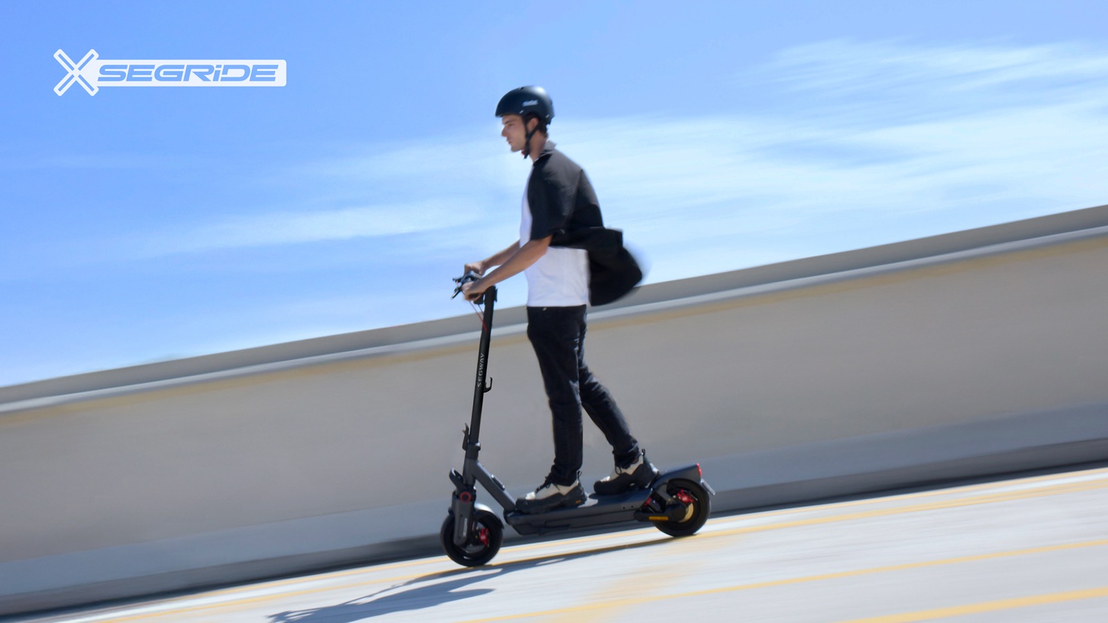 Voksen pendler kjører en Segway Max G3 elsparkesykkel i sol mot blå himmel